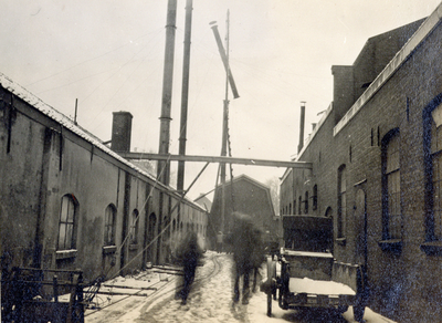 886142 Afbeelding van het stellen van een schoorsteenpijp op een van de gebouwen van de Koninklijke Nederlandsche Lood- ...